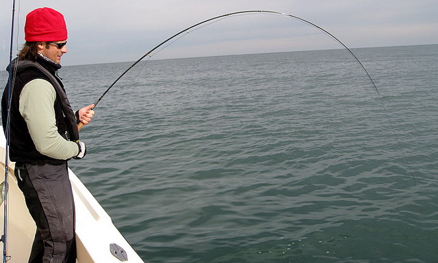 Brandon Hooked up with a Striped Bass on one of his flies wearing a fishing shirt by Lateral Line